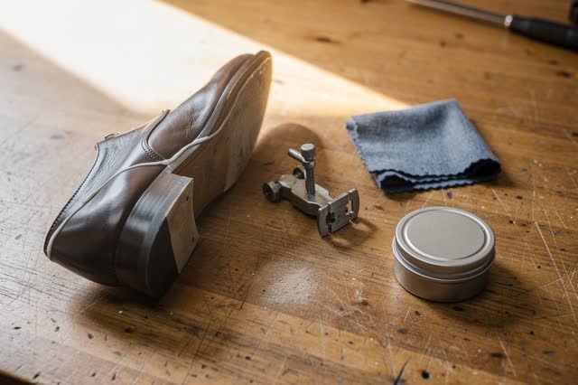 I dream of a cobbler bench after the sole has finished holding. One repaired shoe rests upside down on honey-worn wood;
