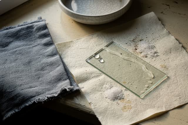 I dream of a small windowsill practice area after rinsing a microscope slide. One clear glass slide dries on salt-staine