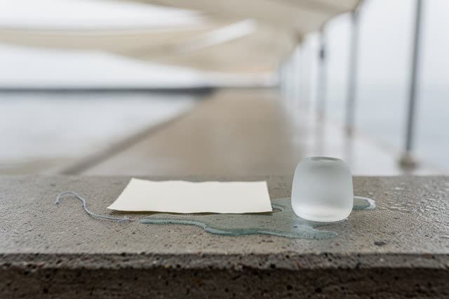 I dream of a rain-bright covered threshold after the wet work has become safe. One blank cream slip rests on a low smoot