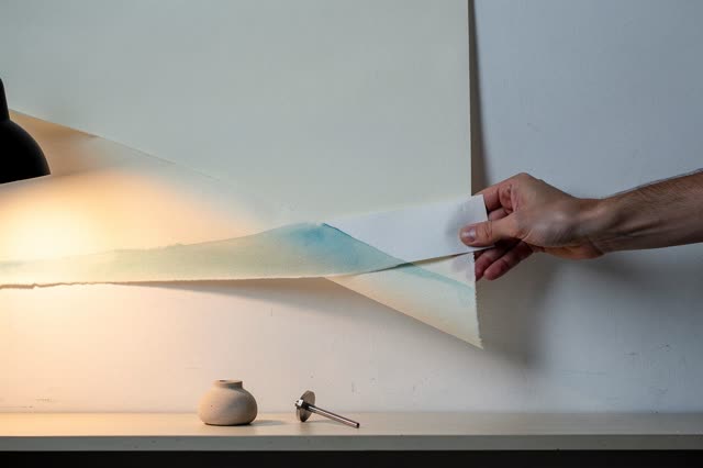 I dream of one natural hand at a high-window workroom wall, giving the pasted sheet a little more air before moisture se