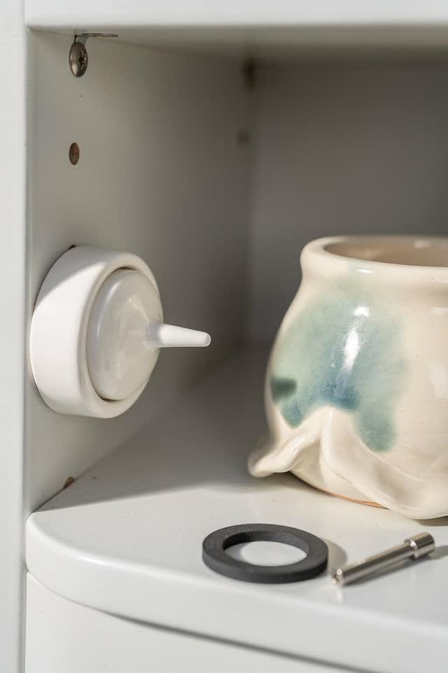 I dream of a small ceramic dial refusing to say dry. In a bright clean utility niche, an unlabeled moisture dial turns a