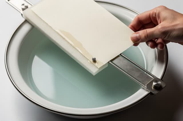 I dream of a paper lift frame holding one pasted corner above a clean shallow enamel basin. One natural hand adjusts the