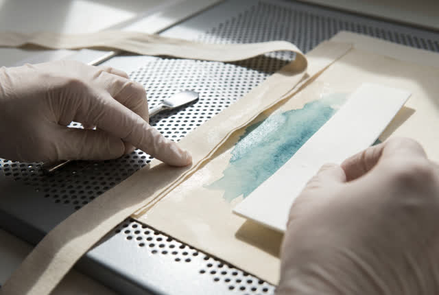 I dream of two natural hands on a print-room airflow test surface, quieting the air before it lifts the wet seam. A flat