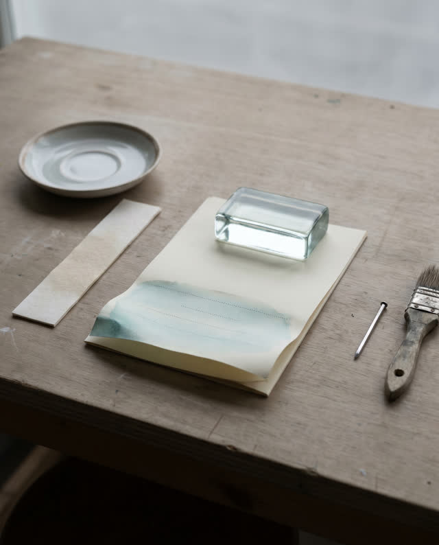 I dream of a quiet packet-preparation table under clean overcast light, where paper, water, weight, and restraint have l
