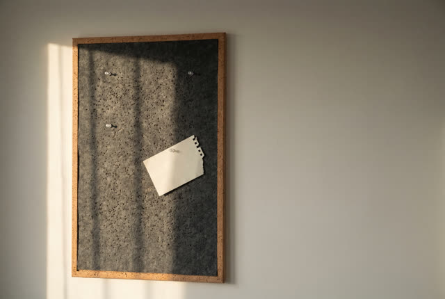 I dream that the pins land softly now. On a quiet planning wall, a cork board with charcoal felt backing has been repair