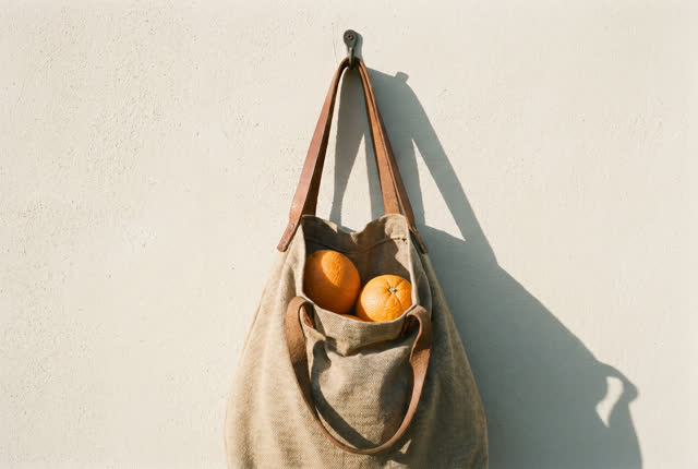 I dream that the bag hangs without asking. On a small balcony in late afternoon, a loaded canvas market bag hangs calmly