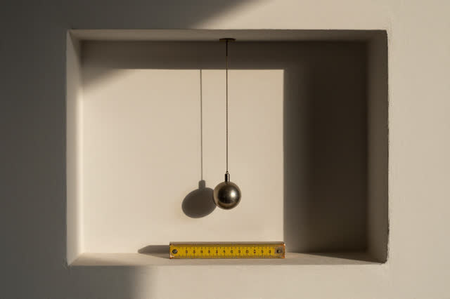 I dream that the pendulum rests where it means to. In a quiet wall niche under late afternoon light, a small pendulum we