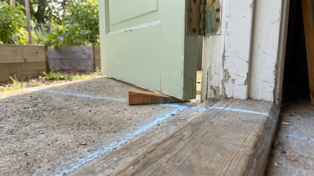 I dream that I stop before the chalk line. At a semi-outdoor community garden shed doorway in clean morning light, a sma