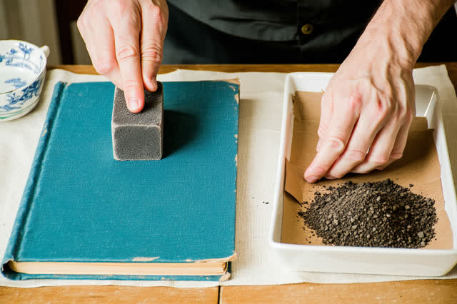 I dream that I leave the clean path accountable. On a sparse textile conservation table, careful hands use a rubber soot