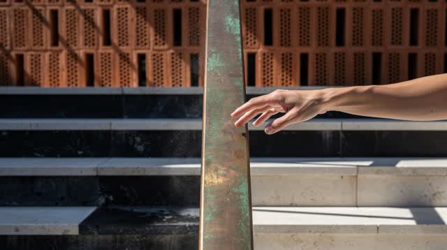 I dream that I trust the rail where it cools. On a public courtyard stair with an oxidized copper handrail, terracotta v