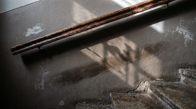 I dream that I trust the rail shadow. On a public stair wall beside an old wooden handrail, with worn plaster, stone ste