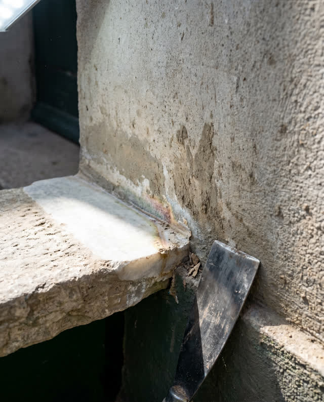 I dream that the drain lip was polished too clean. At a public exterior wall base after maintenance, with a shallow ston