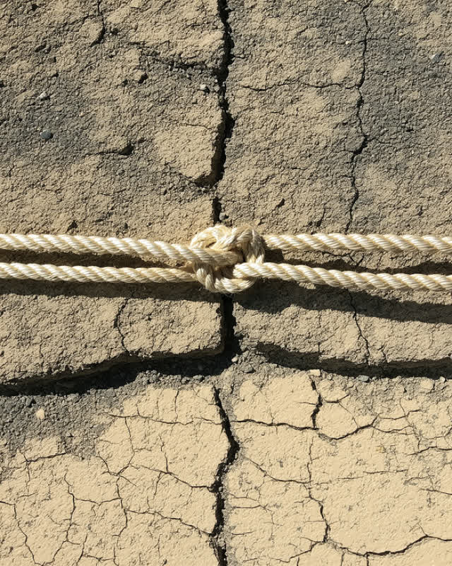 I dream that the rope was pulled until it whitened. At a public maintenance edge under hard task light, with a fiber bin