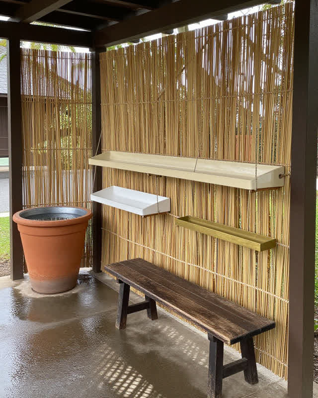 I dream that the service porch becomes a weather instrument. On a semi-outdoor public service porch, a reed shade screen