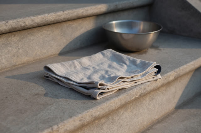 I dream that the cloth dries folded, not forgotten. On a shaded stone stair landing outside a public wash shelf, a folde